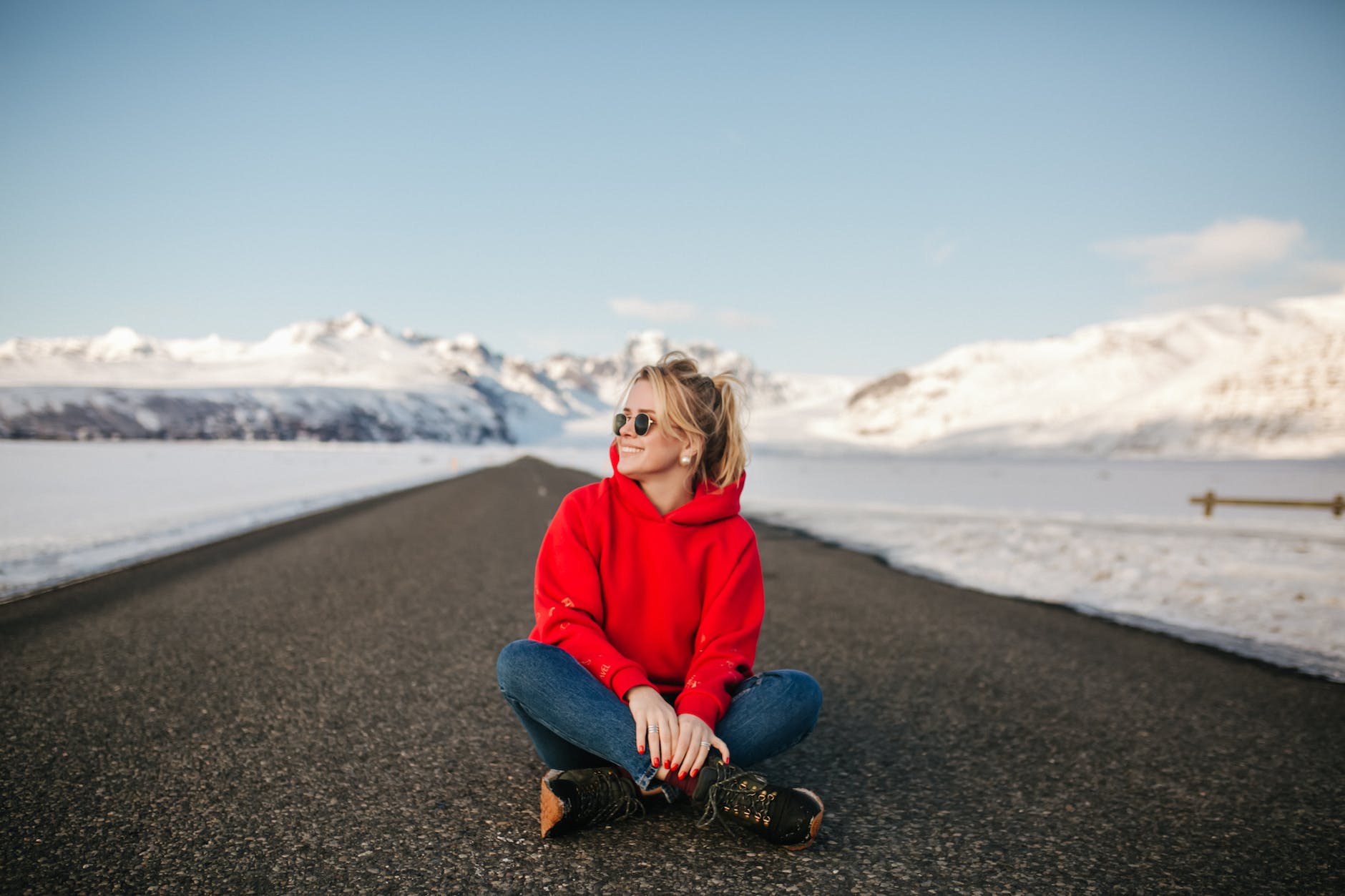 a stylish woman sitting on the road and posing